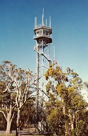 A tall metal tower with a very small enclosed cabin at the top.
