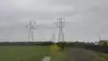 Steel lattice power towers carrying single-circuit and dual-circuit 115 kV / 60 Hz power lines.