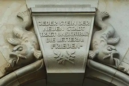 historic=epigraph + location=keystone + inscription=JEDER STEIN DER NEUEN STADT TRÄGT UNSICHTBAR DIE LETTERN: FRIEDEN.