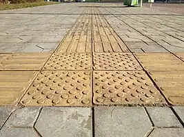 a block of bright yellow tactile pavement at the intersection of 3 guide tactile ways