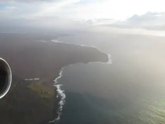 Photo of the coast of Iceland from above with a bit of airplane in view. By Willeke