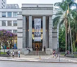 Photograph of the facade of a large stone building with unadorned cuboidal columns