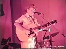 Man on stage with guitar and microphone