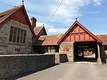 Photograph of the gable end of the schoolroom (dated 1879) and porte-cochère to car park