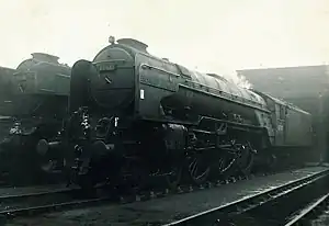 Steam locomotive with four small carrying wheels at the front, six large driving wheels, two small carrying wheels below the cab, and a tender