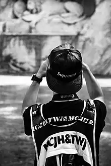 Image 36A man wearing a leather Supreme snapback hat while taking a photograph in 2016 (from 2010s in fashion)