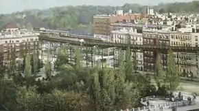 Postcard depicting a forest in Morningside Park with an IRT station and high-rise buildings in the background
